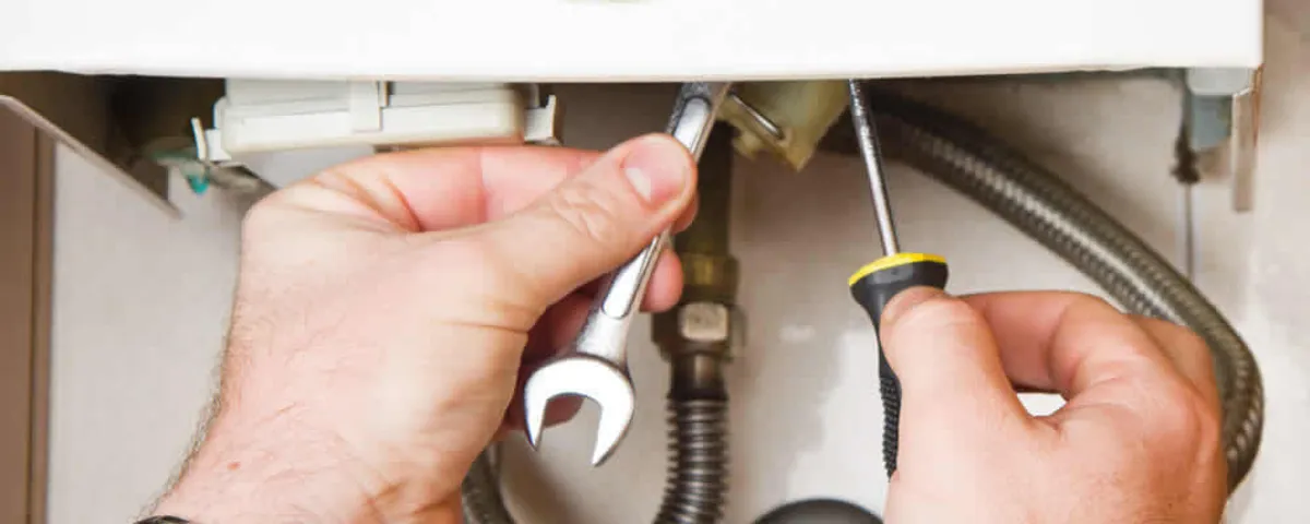 Boiler repair technician tightening pipe fittings and connections in Wellesley, MA