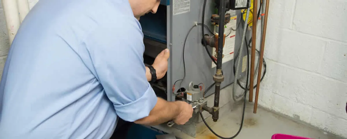 Furnace repair technician inspecting and servicing a home heating system in Wellesley, MA